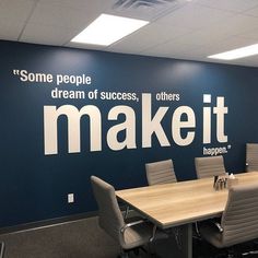 an empty conference room with blue walls and white lettering on the wall that says make it happen