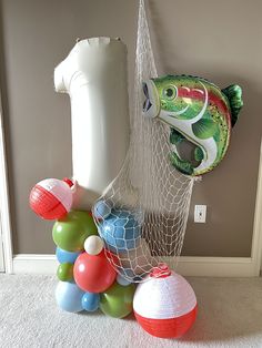 there are many balls and balloons in the room next to an object that looks like a fish