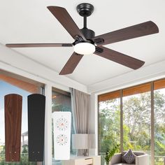 a ceiling fan in a living room next to a couch and table with pillows on it