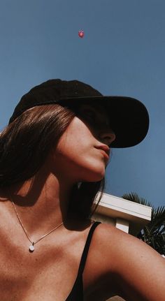 a woman wearing a black hat looking up into the sky