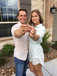 a man and woman taking a selfie in front of a house with their hands together