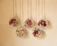 four glass vases filled with flowers hanging on a wall next to a white wall