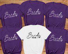 Bride Squad Hen Party T-shirts. Hen party Tees Bride Tribe, Team Bride, Bridal Party Shirts, Bachelorette T-shirts. Wedding tops Hen night. Introducing our fabulous Hen Party T-shirt in Stunning Purple and white! Made with love from 100% cotton, this tee is the perfect addition to any bride and bridesmaid squad, ensuring you look and feel incredible during all your pre-wedding celebrations.  The bride's shirt is a classic white with a beautiful black print. The other hen party members' t-shirts are a Stunning Purple colour with a striking White print. These shirts are not only fashionable but also practical, as they can be worn by both men and women in your group so can give a relaxed fit feel. - Custom: Each t-shirt is carefully handmade to match your bridal party's unique style. We pay a Wedding Tops, Bridesmaid Squad, Bridal Party Shirts Bachelorette, Bachelorette T Shirts, Party T Shirts, Bachelorette Tshirts, Hen Night, Bridal Party Shirts, Personalized Bride