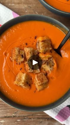 two bowls of tomato soup with croutons on top