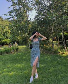 a woman standing in the grass with her hands on her head