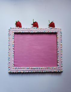 a pink frame with two strawberries on top