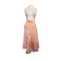 "Orange & White Tiered Midaxi Skirt with White Cotton Tassel Fringes and a Border of Blue.  Elastic Waist, Side Pockets, Midweight Fabric. Floral print. Comfortable and pleasant to the body.  Mannequin in photo is 5'7\" tall.  92% Polyester, 8% Spandex." Orange Beach Skirt With Elastic Waistband, Orange Midi Skirt For Beach, Orange Lined Skirt For Vacation, Vacation Orange Lined Skirt, Flowy Beach Skirt In Orange, Orange Flowy Beach Skirt, Orange Relaxed Maxi Skirt For Beach, Orange Tiered Lined Skirt, Orange Tiered Skirt With Elastic Waistband