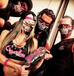 two women with painted face paint and one man holding a wrestling belt in front of them