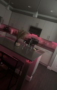 a kitchen with an island and pink lighting