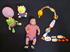 a baby laying on the ground surrounded by toys