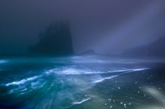 the ocean is very dark and blue with light coming from it's headlight