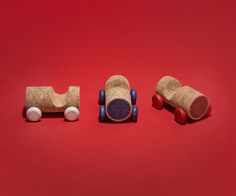 three toy cars made out of corks on a red background