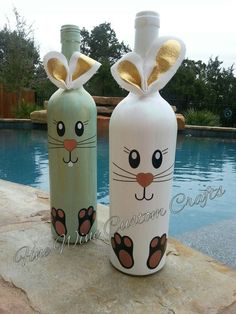 two decorative bottles sitting on top of a rock next to a swimming pool with a cat design