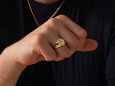 a man wearing a gold signet ring on his finger