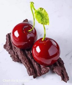 two cherries sitting on top of a piece of wood