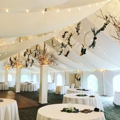 the inside of a tent with tables and white linens, decorated with christmas wreaths