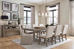 a dining room table and chairs with pictures on the wall behind it in front of windows