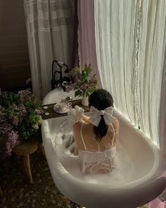 a woman sitting in a bathtub with flowers on the side