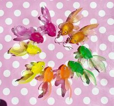 four goldfish are in a circle on a pink and white polka dot tablecloth