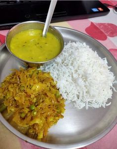 a silver plate topped with rice and curry