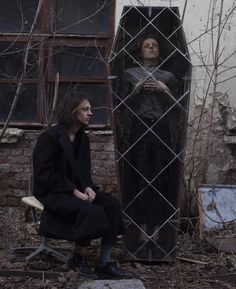 a man sitting in front of a mirror next to a statue