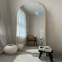 a large mirror sitting on top of a floor next to a table with a candle