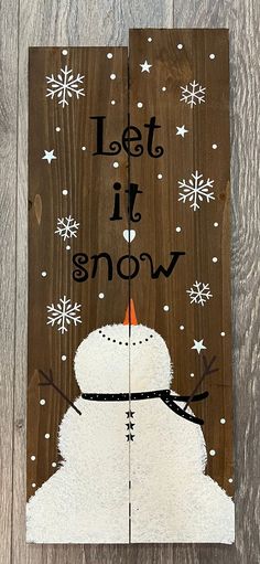 a wooden sign that says, let it snow with a snowman wearing a hat