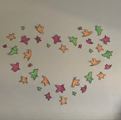 the wall is decorated with many different colored paper stars and shapes that are arranged in a heart shape