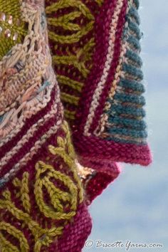 a close up of a knitted scarf hanging from a hook on a clothes line