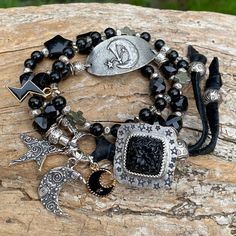 Moody black boho bracelet with a beautiful and unique artisan custom carved black Onyx and hand stamped 925 silver button closure.  6mm round Shungite beads, black Tourmaline 10mm faceted square beads. Very unique artisan pewter Moon Goddess focal bracelet link and Karen Hill Tribe fine silver beads and link. Artisan sterling silver whimsical crescent moon and star charms, black Onyx 15mm star beads, pewter cross beads, enamel crescent moon charm and lightening bolt charm,  3 artisan sterling si Adjustable Black Bohemian Beaded Bracelets, Festival Jewelry With Unique Black Variations, Handmade Onyx Black Bracelets, Handmade Black Onyx Bracelets, Black Hand Wrapped Beaded Bracelets For Festival, Hand Wrapped Black Beaded Bracelets For Festivals, Handmade Symbolic Black Beaded Bracelets, Unique Black Obsidian Jewelry, Festival Hand-wrapped Black Beaded Bracelets