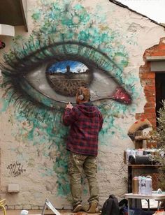 a man standing in front of a wall with an eye painted on it