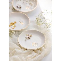 two white plates with gold letters on them and some flowers in the middle one is empty