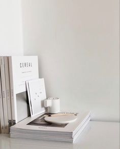 a stack of books sitting on top of a table next to a cup and saucer