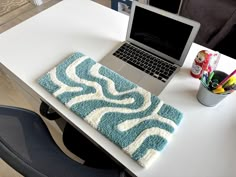 a laptop computer sitting on top of a white desk next to a blue and white rug