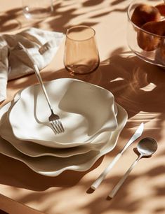 a table topped with plates and silverware next to a bowl filled with peaches