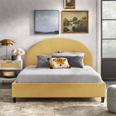 a yellow bed sitting in a bedroom next to a window with pictures on the wall