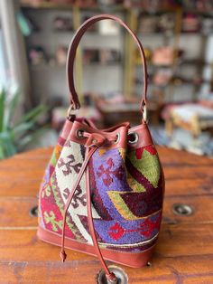 Thank you for visiting our shop!  It's very useful bag as shoulder and as crossbody bag.  This bag is spacious and holds a lot of things. Size         : 30cm x 27cm x 8cm Material  : wool / leather We select beautiful vintage kilims from all over the anatolian area and middle east area. and We do special wash for Kilim rug first, after that cut the kilim to remake unique kilim bags at our atelier  one by one. All products have been produced in a smoke-free environment.  Vintage kilim with colore Multicolor Everyday Bucket Shoulder Bag, Everyday Multicolor Bucket Shoulder Bag, Gift Leather Handles Bucket Bag, Bohemian Bucket Bag With Adjustable Strap For Shopping, Multicolor Bucket Bag For Travel, Multicolor Bucket Shoulder Bag With Adjustable Strap, Travel Bucket Shape Hobo Bag With Leather Handles, Everyday Bucket Shoulder Bag With Detachable Strap, Travel Bags With Leather Handles And Bucket Shape