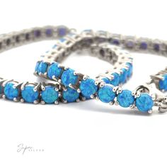 Brilliant Blue Opal Bracelet adorned with bright blue lab-created opal stones, closely interconnected, arranged on a white surface, showing detailed craftwork. Opal Bracelet, Blue Opal, Prong Setting, Opal, Vibrant Colors, Sparkle, 925 Sterling Silver, Turquoise, Bracelet