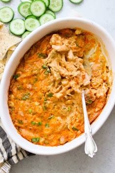 a white bowl filled with chicken enchilada soup next to sliced cucumbers