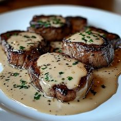 some meat with gravy on top of it sitting on a white plate in a sauce