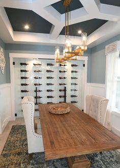 a dining room with a wooden table surrounded by white chairs and chandelier hanging from the ceiling