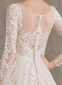 the back of a woman's wedding dress with sheer sleeves and beaded details