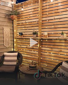 an outdoor patio with string lights on the fence and chairs around it, along with potted plants