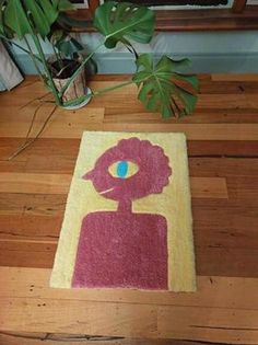 a rug with an image of a woman's face on the floor next to a potted plant