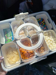 a person holding a plastic container filled with different types of food and snacks in it