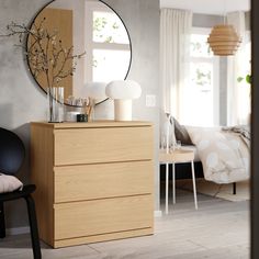 a bedroom scene with focus on the dresser and bed in the background, along with a round mirror