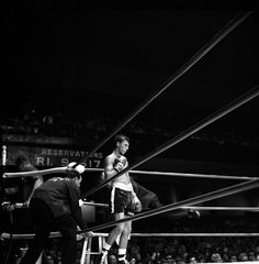 two men standing on top of a ladder in front of an audience at a boxing match