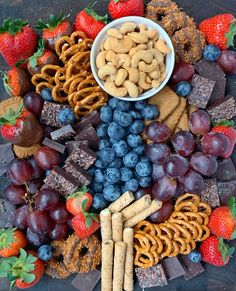 a platter filled with fruit, crackers and pretzels next to chocolate covered strawberries