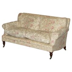 an old fashioned couch with floral fabric on the back and arms, sitting in front of a white background