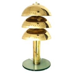 three tiered brass plated table lamp on glass base with circular light fixture in the middle